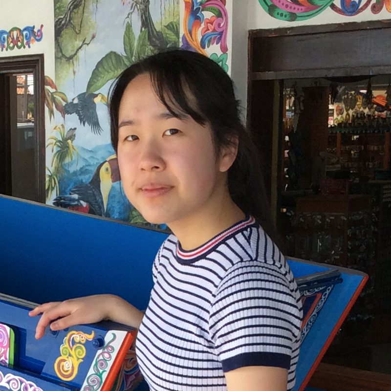 Ashley Bang in front of a shop. Colorful designs cover the walls and furniture.
